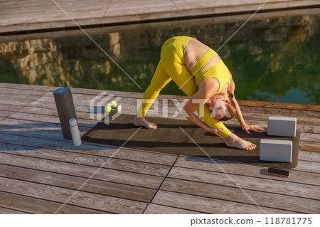 Engaging in a Yoga Practice by the Water in Chic and Stylish Activewear Attire to Unwind 118781775