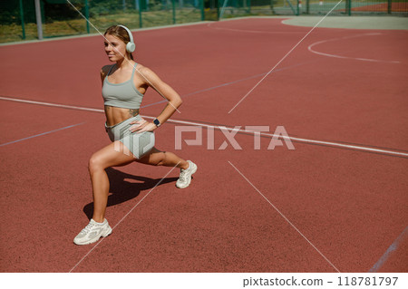 A dedicated fitness enthusiast is lunging energetically on an outdoor court for their workout A dedicated fitness enthusiast is lunging energetically on an outdoor court for their workout 118781797