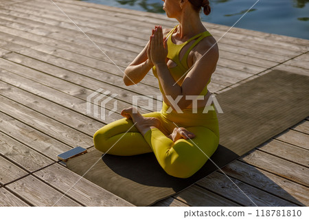 Engaging in a Peaceful Yoga Practice by the Water while Adorned in Vibrant Yellow Attire 118781810