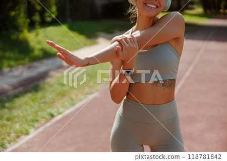 A Fit and Active Woman Engaging in Stretching Exercises Outdoors While Wearing Athletic Gear A Fit and Active Woman Engaging in Stretching Exercises Outdoors While Wearing Athletic Gear 118781842