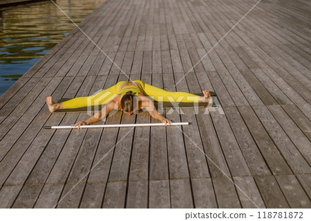 A graceful Flexible Stretching Pose on a Dock by calm Water, showcasing tranquility and balance A graceful Flexible Stretching Pose on a Dock by calm Water, showcasing tranquility and balance 118781872