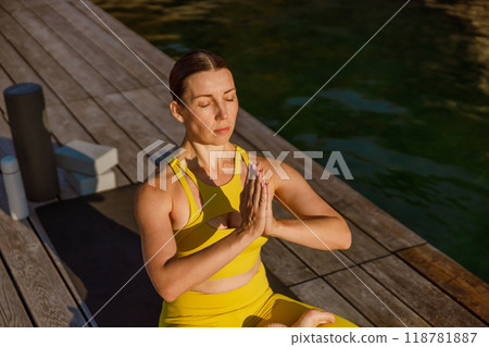 A Woman Practicing Yoga by the Water in a Beautiful Yellow Outfit Enjoying Nature A Woman Practicing Yoga by the Water in a Beautiful Yellow Outfit Enjoying Nature 118781887