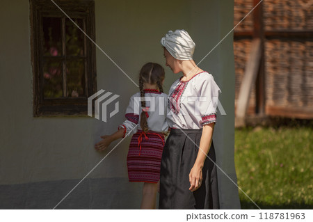 Woman and girl standing in front of building, smiling happily Woman and girl standing in front of building, smiling happily 118781963