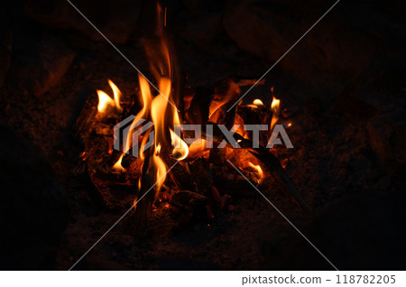 Campfire at touristic camp. Burning wood. Flame and fire sparks on dark background. Campfire at touristic camp. Burning wood. Flame and fire sparks on dark background. 118782205