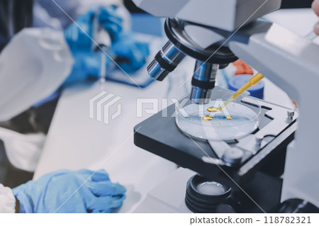 Scientist using microscope in laboratory. Close-up of a researcher's hands adjusting a modern microscope in a lab setting. Science concept Scientist using microscope in laboratory. Close-up of a researcher's hands adjusting a modern microscope in a lab setting. Science concept 118782321