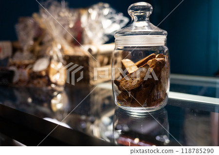 A glass jar of sweet rusks sits on a cafe display. Subdued light, selective focus. A glass jar of sweet rusks sits on a cafe display. Subdued light, selective focus. 118785290