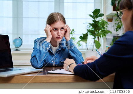Sad upset young teenage female patient talking to professional mental therapist Sad upset young teenage female patient talking to professional mental therapist 118785806