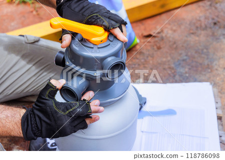 Maintenance worker assembles sand filter system tank, equipment used to clean swimming pools Maintenance worker assembles sand filter system tank, equipment used to clean swimming pools 118786098