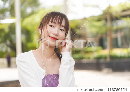 Young adult asian college student woman use earphone listening for music with smile happy face Young adult asian college student woman use earphone listening for music with smile happy face 118786754