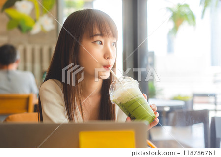 Young adult business southeast asian woman with long hair drinking matcha at indoor cafe on day 118786761