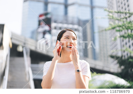Happy young adult asian business single woman use mobile phone talking with friend city background. Happy young adult asian business single woman use mobile phone talking with friend city background. 118786970
