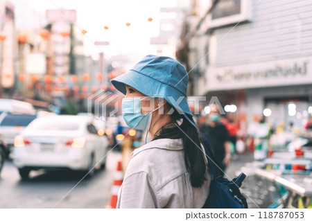 Walking young adult asian woman traveller wear face mask for covid-19 traveling in local city on summer day Walking young adult asian woman traveller wear face mask for covid-19 traveling in local city on summer day 118787053