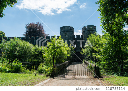 The tower and walls of Cardiff Castle surrounded by greenery under bright sunlight in Cardiff, the capital of Wales 118787114