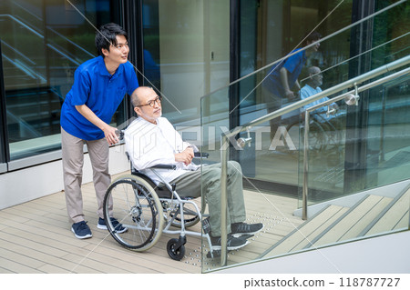 Seniors in wheelchairs having trouble climbing stairs and care facility staff 118787727