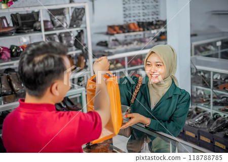 hijab customer taking purchased product from male staff hijab customer taking purchased product from male staff 118788785