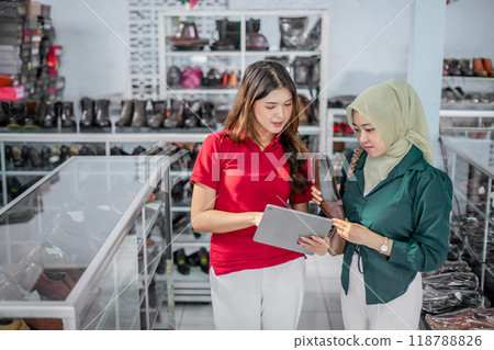 female staff helping hijab customer to checking heels supplies female staff helping hijab customer to checking heels supplies 118788826