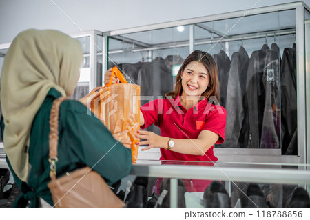 female staff giving purchased leather product to hijab customer female staff giving purchased leather product to hijab customer 118788856