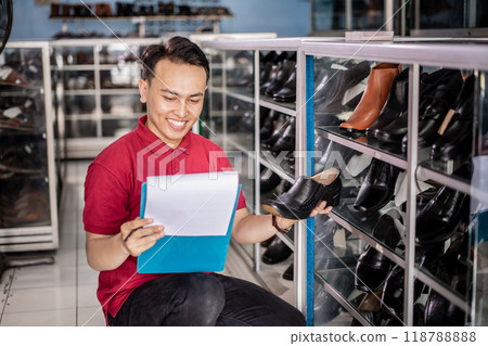 male employee in red polo shirt holding leather shoes and clipboard male employee in red polo shirt holding leather shoes and clipboard 118788888