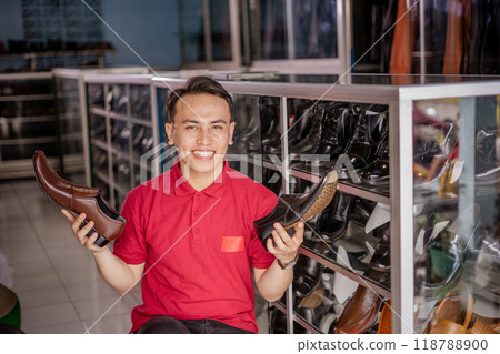 half body picture of indonesian seller holding black and brown leather shoes half body picture of indonesian seller holding black and brown leather shoes 118788900