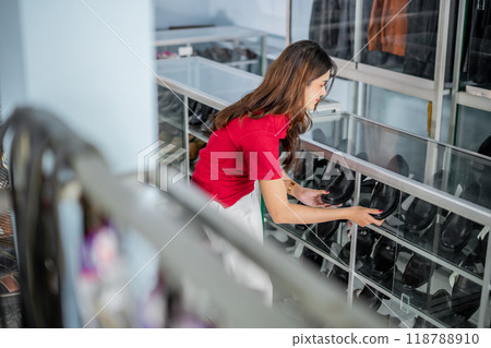 female staff putting black leather shoes into display shelf female staff putting black leather shoes into display shelf 118788910
