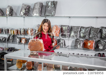 female employee looking at leather bag and holding tablet female employee looking at leather bag and holding tablet 118788958