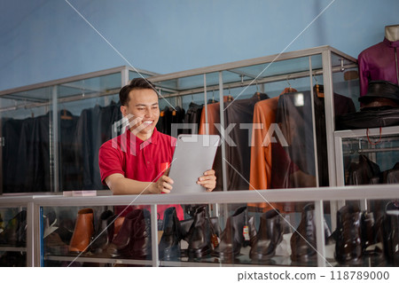leather shoe salesman wearing red polo shirt holding tablet 118789000