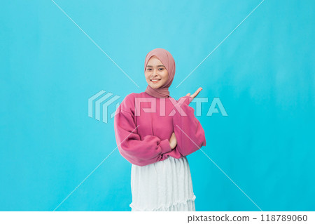 A Cheerful Young Woman Gesturing Happily Against a Bright Blue Background, Radiating Positivity and Joy 118789060