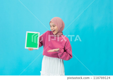A Cheerful Young Woman Holding a Vibrant Green Frame Against a Bright Blue Background for Visual Appeal 118789124