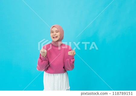 A young woman in casual style and fashionable accessories poses against a bright blue background A young woman in casual style and fashionable accessories poses against a bright blue background 118789151