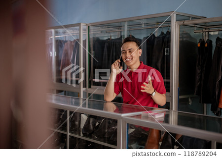 asian salesman in leather shoes store speaking on phone 118789204