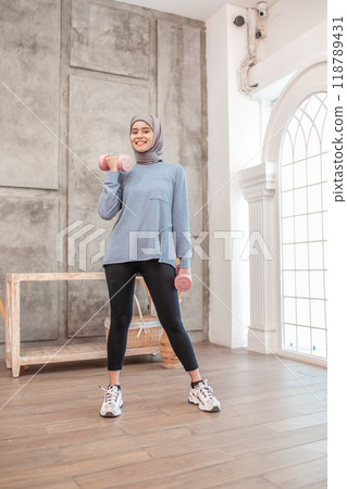 A Woman Engaged in Fitness Exercising with Dumbbells in a Contemporary Studio Setting A Woman Engaged in Fitness Exercising with Dumbbells in a Contemporary Studio Setting 118789431