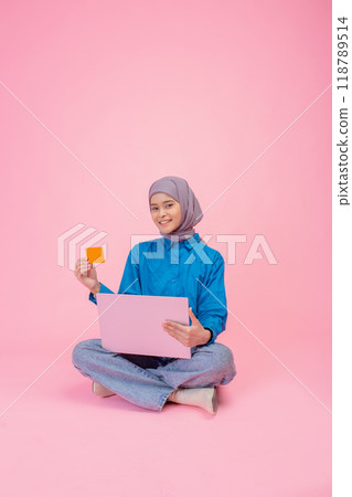 Young Woman with Laptop and Card Against Pink Background Representation of Digital Engagement Young Woman with Laptop and Card Against Pink Background Representation of Digital Engagement 118789514