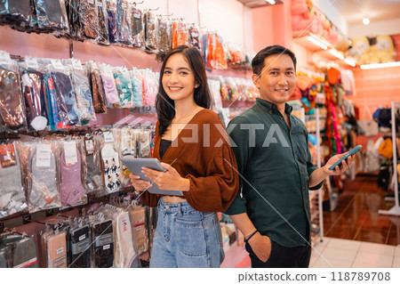 woman and man standing holding a mobile phone and tab 118789708