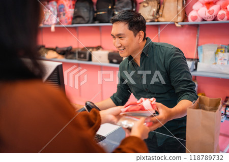 male shopkeeper looking at computer screen while checking shopping items male shopkeeper looking at computer screen while checking shopping items 118789732
