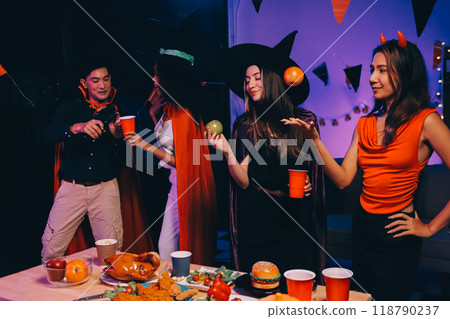 Joyful office Halloween party with coworkers in costumes, celebrating with drinks and laughter, fostering teamwork and festive spirit 118790237
