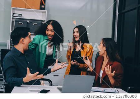 Young corporate employees sitting in office looking at laptop screen reading good news excited happy team diverse people celebrating victory win command success excellent result professional teamwork 118790300