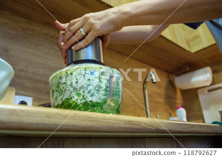 Preparing fresh herb mixture in a kitchen using a food processor 118792627
