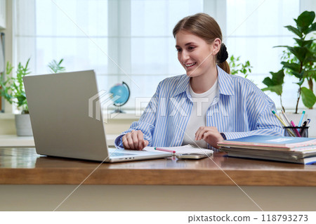 Teenage girl student studying online sitting at home at desk using laptop for video conference Teenage girl student studying online sitting at home at desk using laptop for video conference 118793273