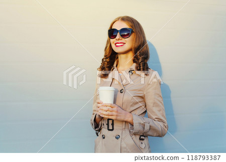portrait happy smiling woman holding cup of coffee wearing sunglasses on city street portrait happy smiling woman holding cup of coffee wearing sunglasses on city street 118793387