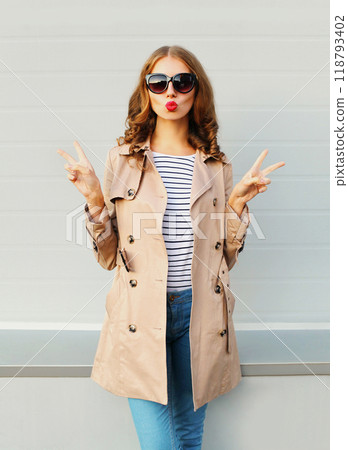 Fashion pretty young woman blowing kiss wearing a black sunglasses coat over grey background 118793402