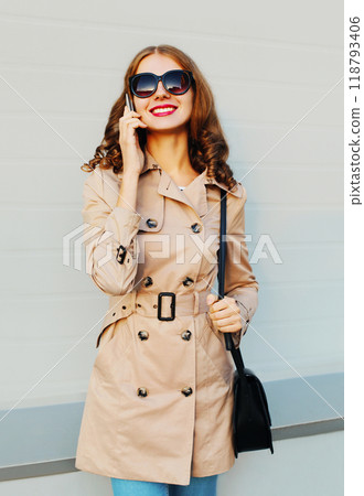 Happy beautiful young woman talking on smartphone standing on grey background 118793406