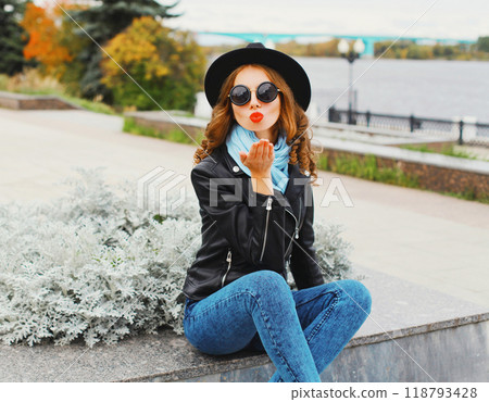 Fashion portrait young woman blowing a kiss wearing black hat in city park Fashion portrait young woman blowing a kiss wearing black hat in city park 118793428
