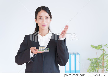 Real estate saleswoman holding a model of a house 118794167