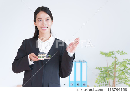 Real estate saleswoman holding a model of a house Real estate saleswoman holding a model of a house 118794168