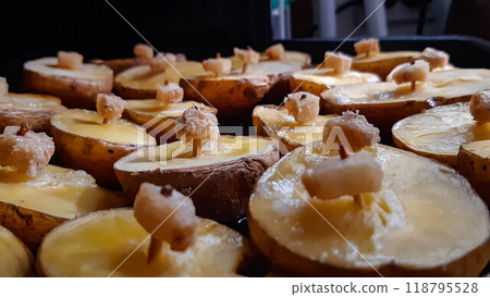 Baked potatoes in the oven. Ruddy potatoes with a piece of lard on a match. A very tasty dish. 118795528