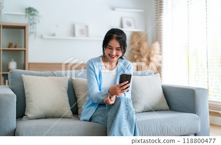 Smiling pretty young Asian woman sitting on cozy couch 118800477