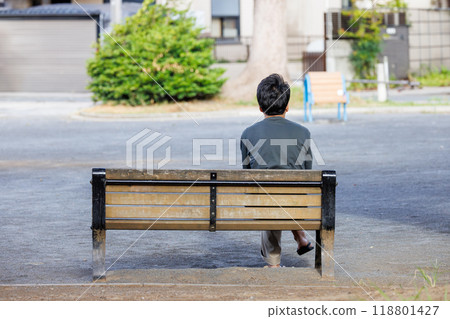 A man sitting on a park bench 118801427