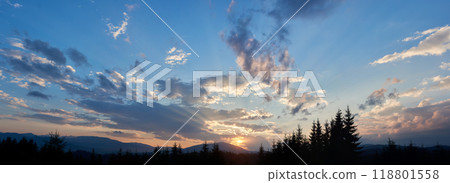 Sun sets behind range of distant mountains, casting golden rays through clouds. Sky, painted with shades of blue, pink, and gold, in tranquil evening. Silhouetted pine trees add depth to landscape. Sun sets behind range of distant mountains, casting golden rays through clouds. Sky, painted with shades of blue, pink, and gold, in tranquil evening. Silhouetted pine trees add depth to landscape. 118801558