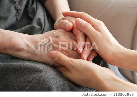 A woman's hand holding an elderly woman's hand A woman's hand holding an elderly woman's hand 118802956
