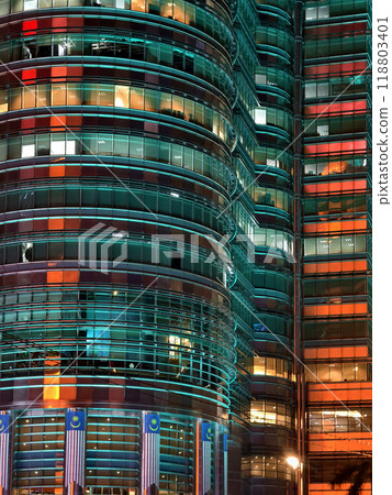 A tall building featuring numerous windows shines brightly at night 118803401